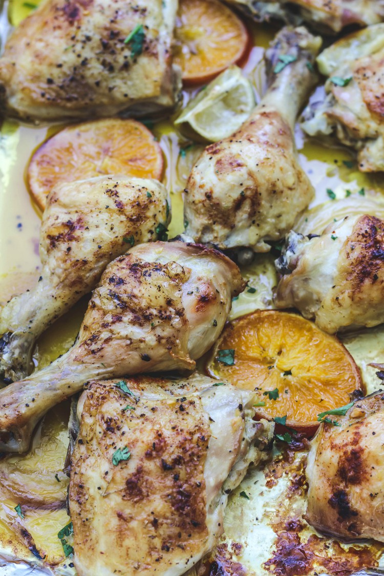 overhead image of chicken and oranges on a pan