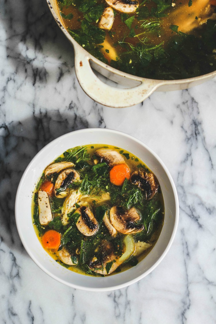 overhead image of mushroom vegetable soup in a white bowl on marble background