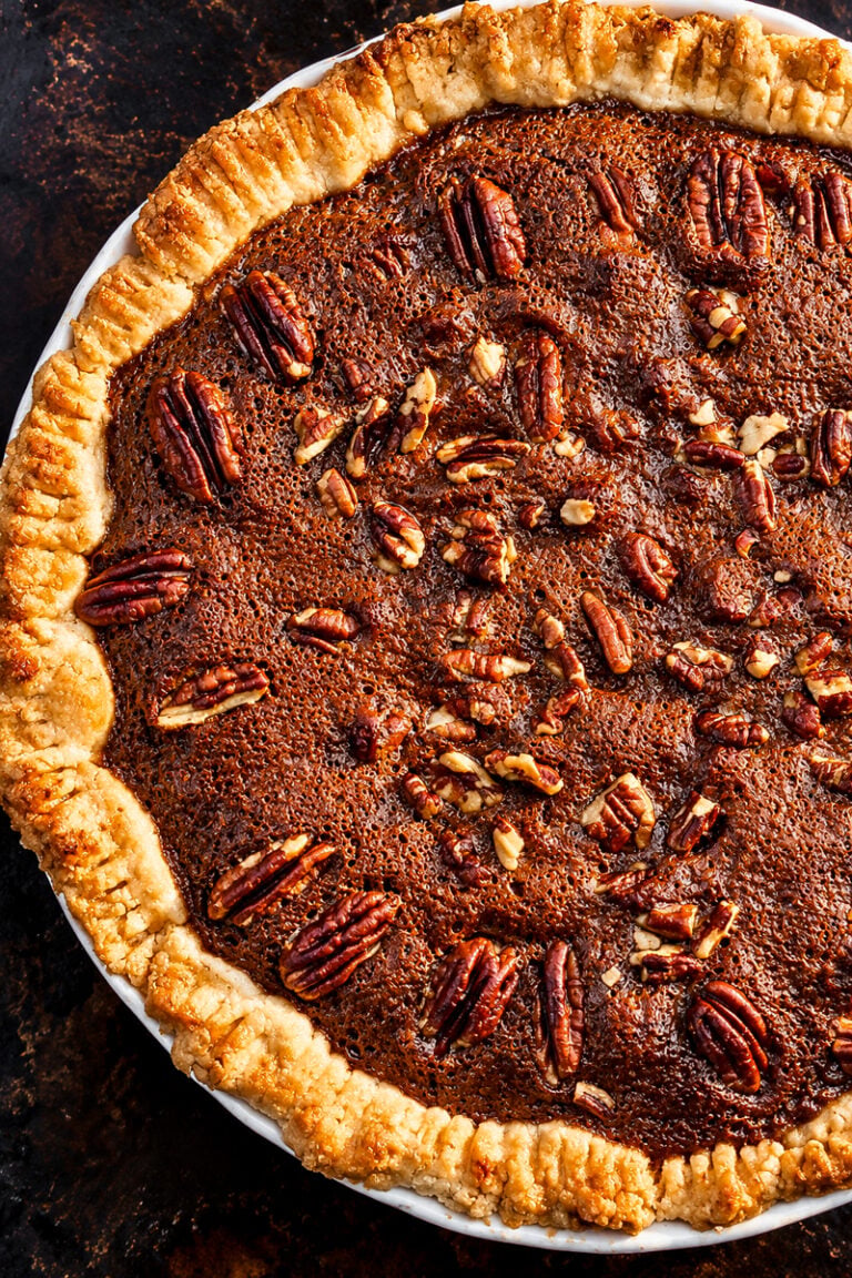 Chocolate espresso pecan pie with a pecan-half border on a holiday table
