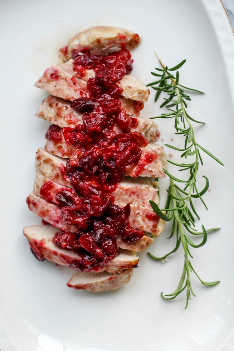 overhead image of baked cranberry glazed turkey tenderloin on white plate. 