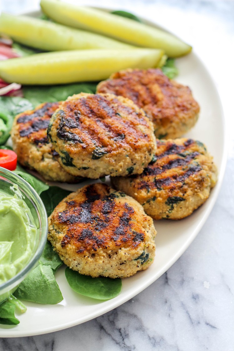 overhead image of spinach chicken burgers on a white plate