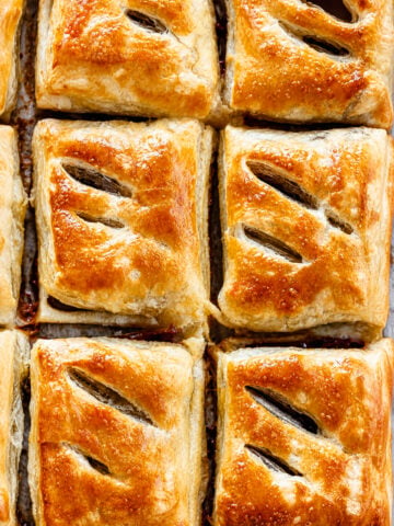 Golden brown, flaky Pastelitos de Guayaba–Cuban Guava Pastries with three diagonal slits on top, arranged closely together in a grid pattern on a baking tray.