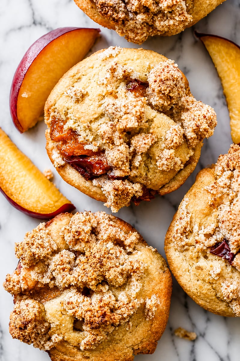Close up of a peach streusel muffin split open showing juicy peach pieces inside the soft crumb