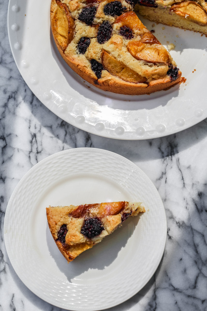 image of a slice of a gluten free peach and blackberry cake on white plates