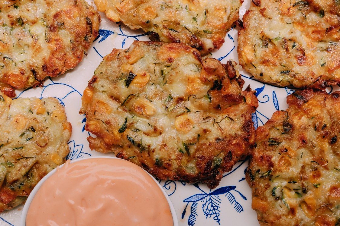 overhead image of zucchini and corn fritter on a serving plate.