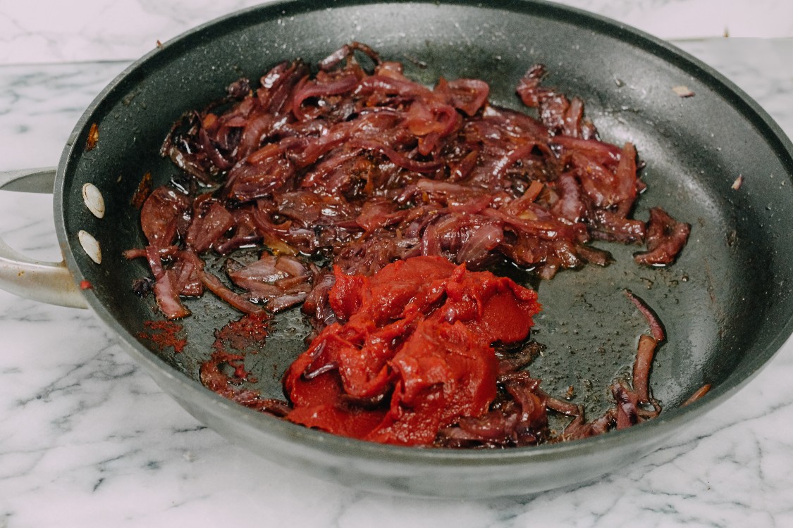 image of tomato paste in a skillet with onions