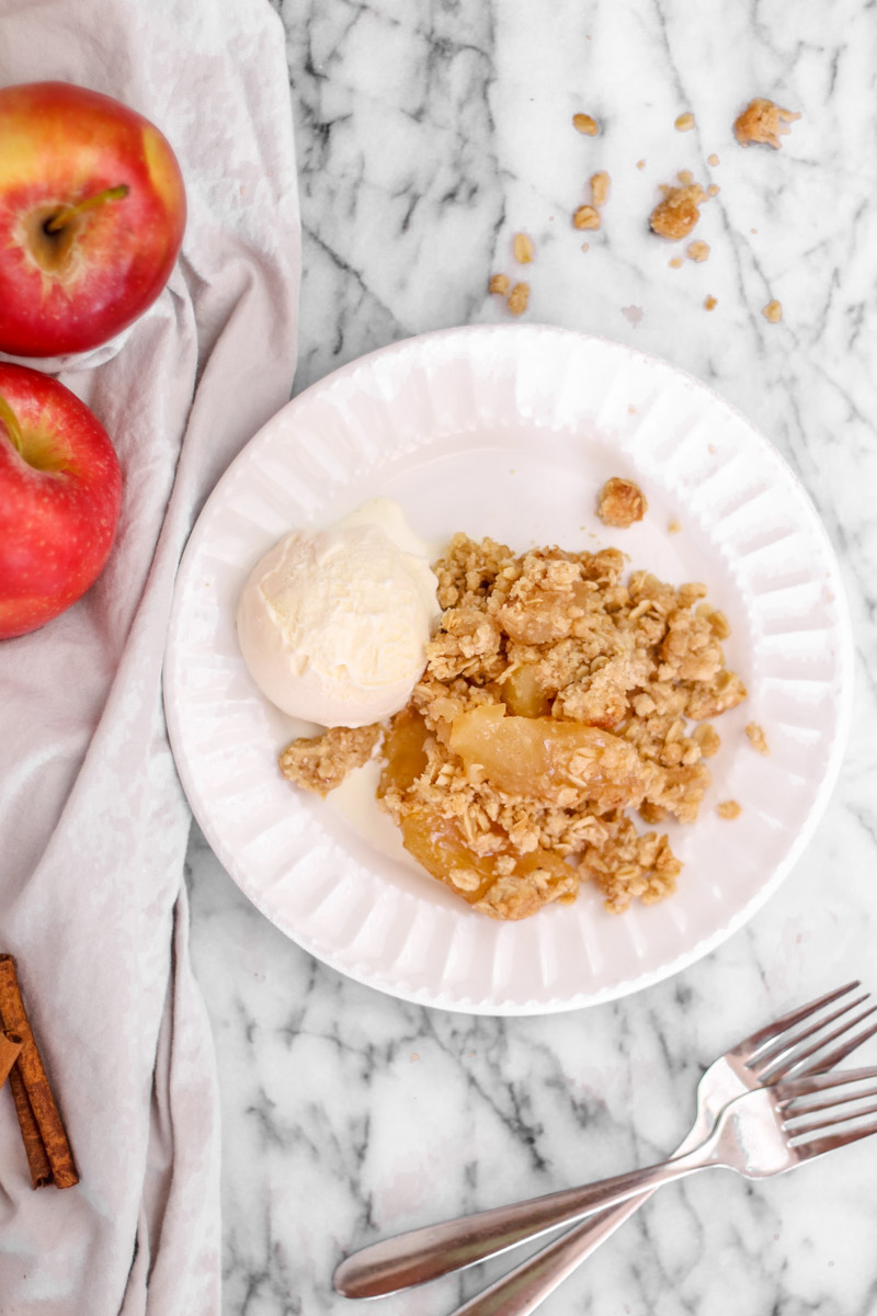 overhead image of cinnamon apple crisp on a white plate.