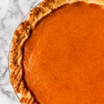 Vegan pumpkin pie topped with a pie dough letter V for vegan
