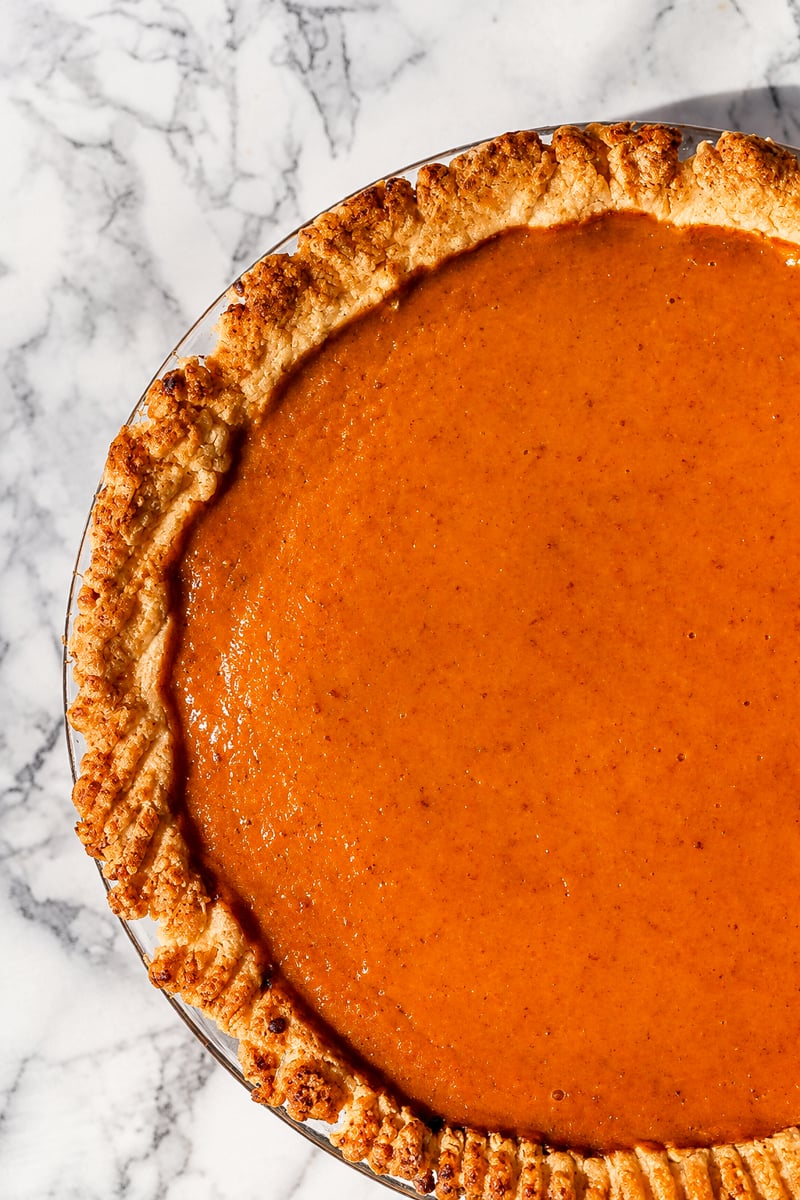 Vegan pumpkin pie topped with a pie dough letter V for vegan