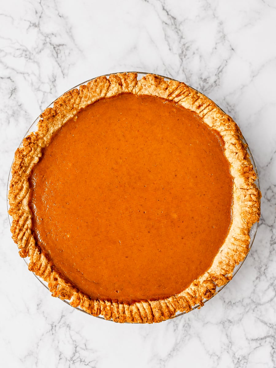 Vegan pumpkin pie topped with a pie dough letter V for vegan