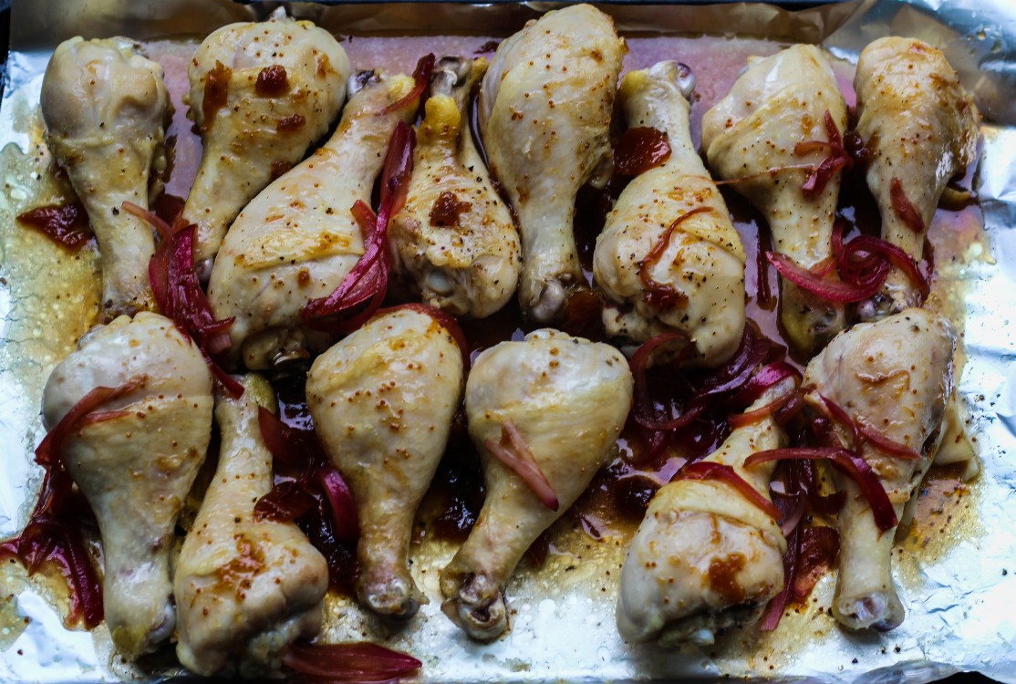 overhead image of making balsamic and fig glazed chicken with caramelized onions on a baking sheet