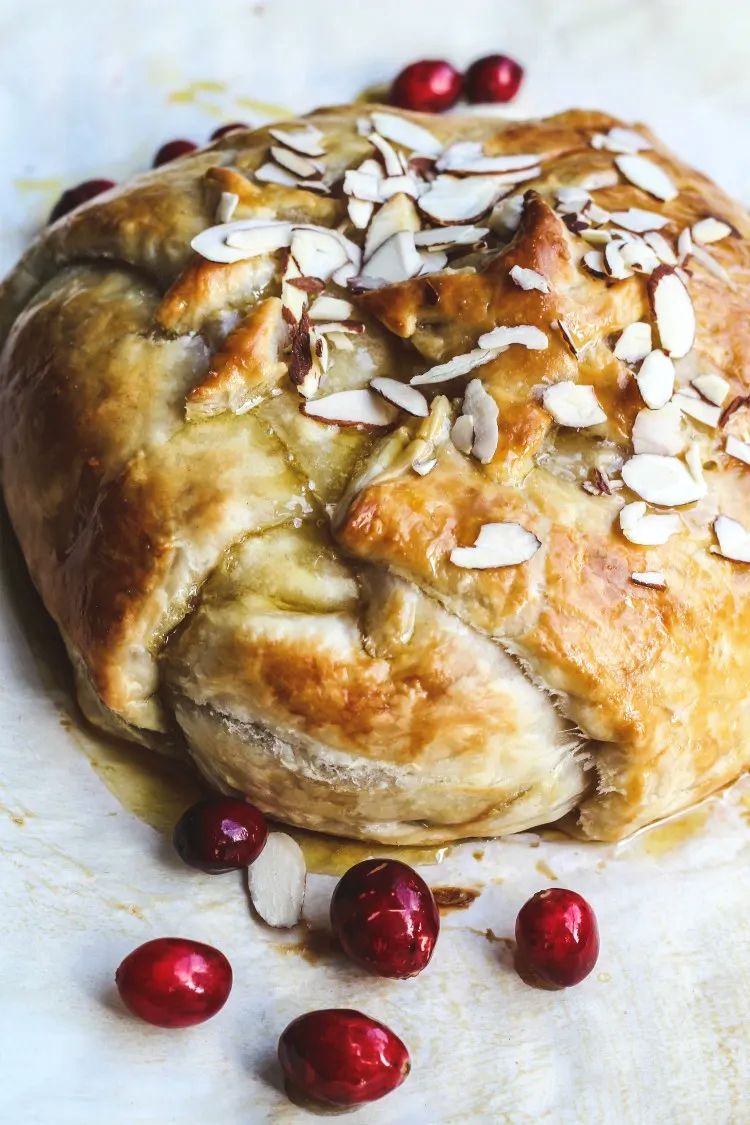 image of baked brie in puff pastry with cranberries on parchment paper