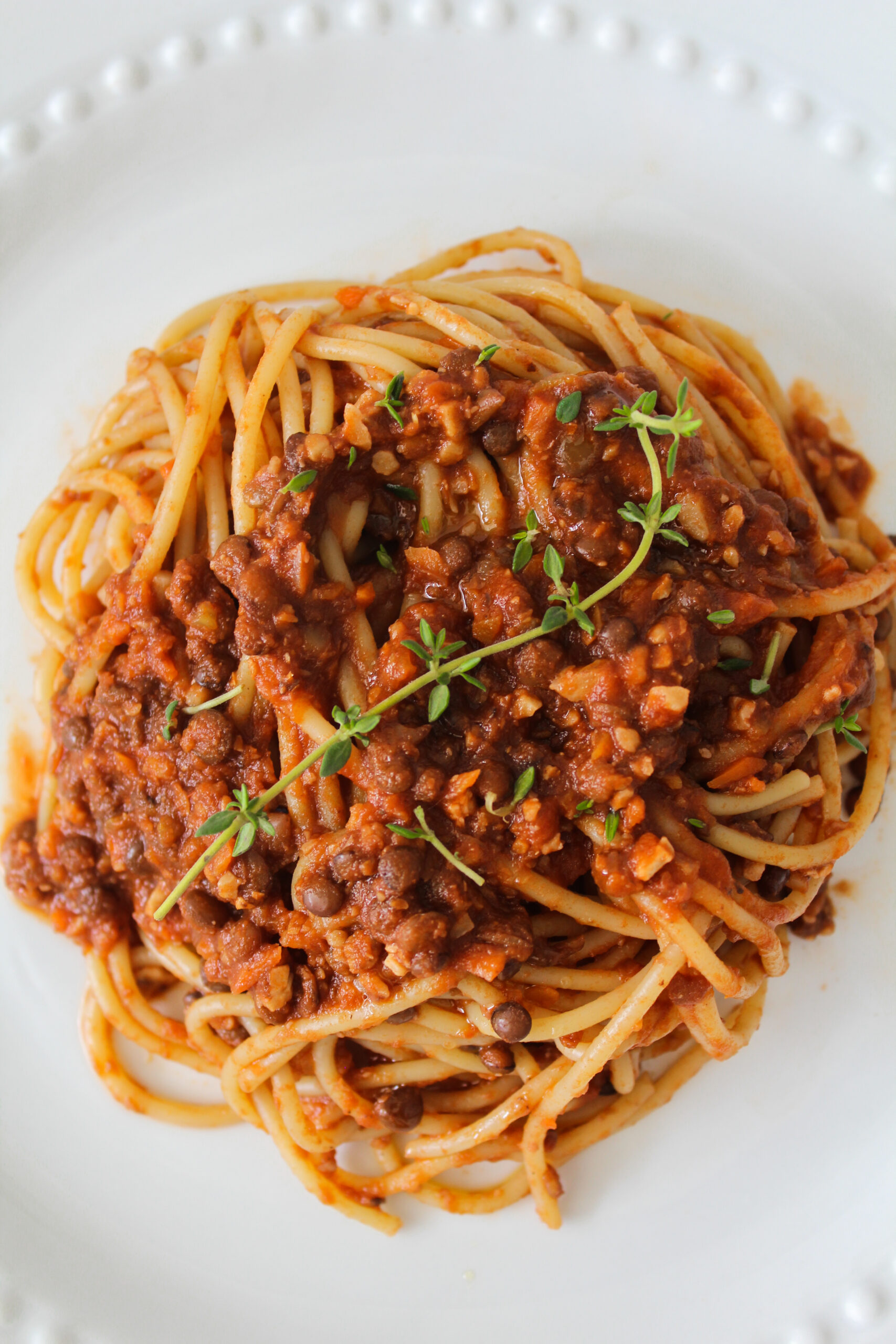 overhead image of easy lentil bolognese with spaghetti on a white plate