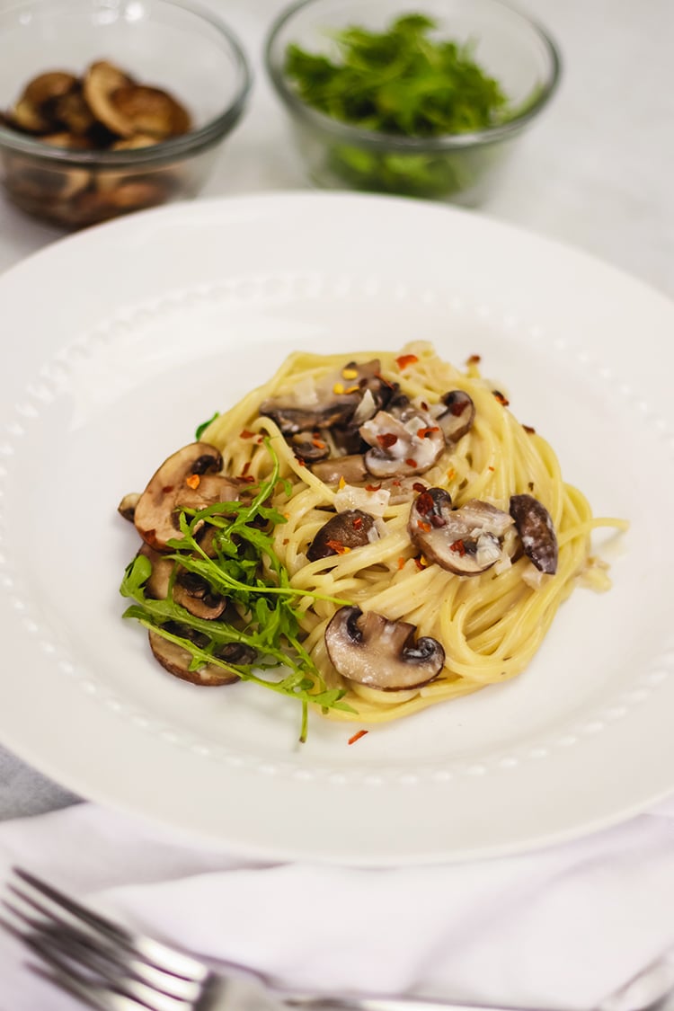 image of pasta on a white plate and small glass dishes and background.