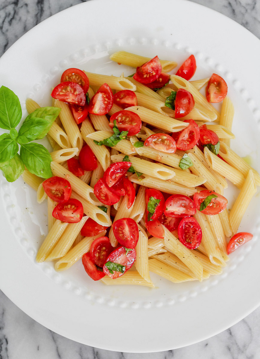 overhead image of vegan cherry tomato pasta on a white plate