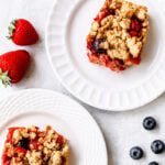 Sliced mixed berry crumble bars on parchment paper showing jammy blueberry and raspberry filling