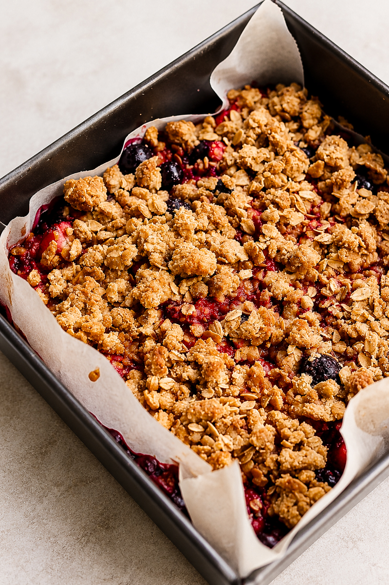 Overhead view of berry crumble bars in an 8x8 pan with golden oat topping