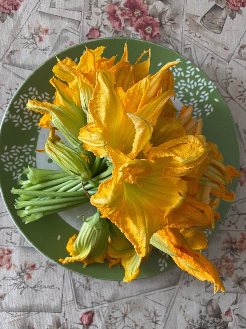 image of a bouquet of zucchini flowers on a green plate.