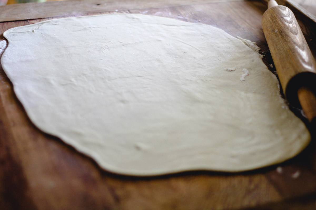 overhead image of rolling out Homemade Sardinian Culurgiones dough on a wooden board