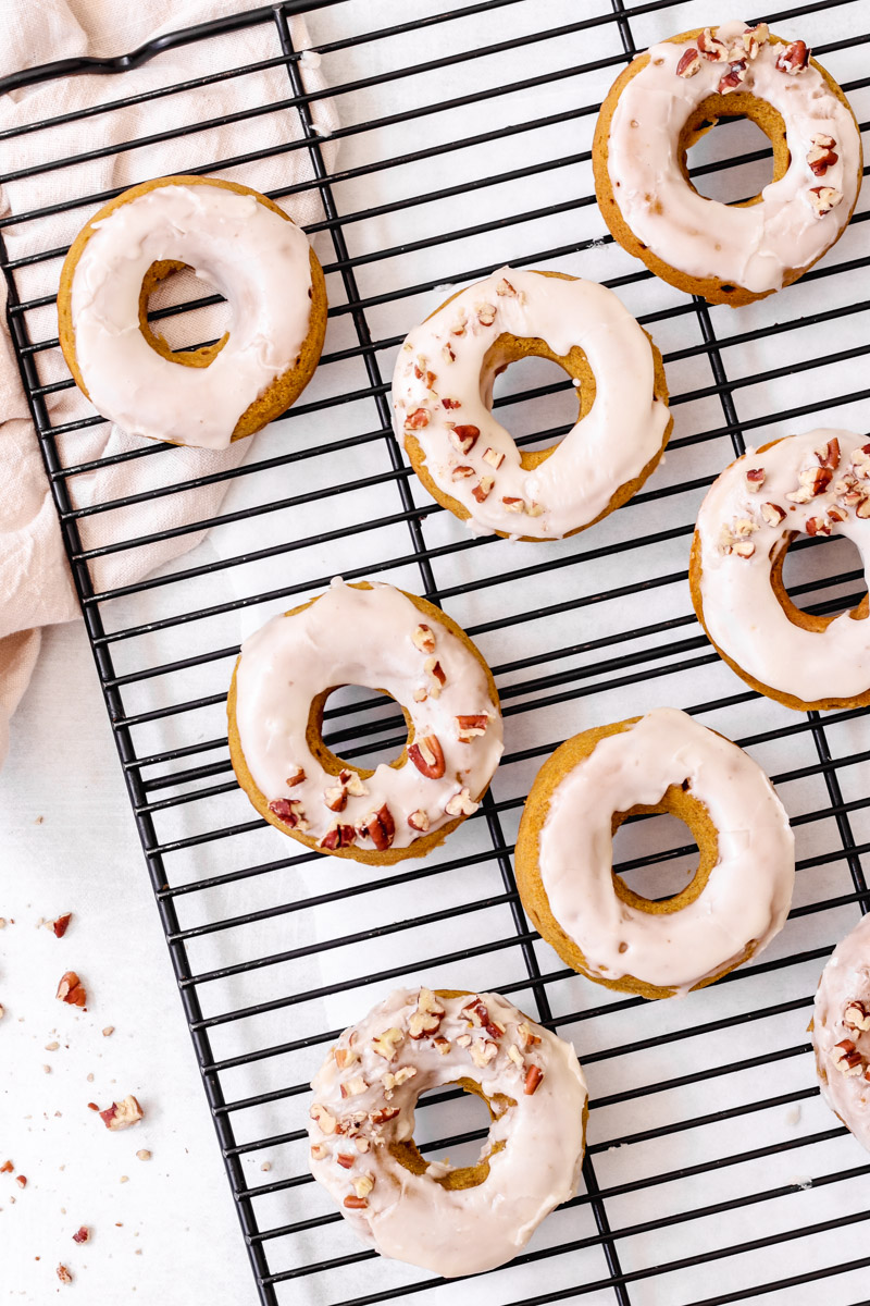 overhead image of easy baked pumpkin donuts on a baking rack and napkin in background