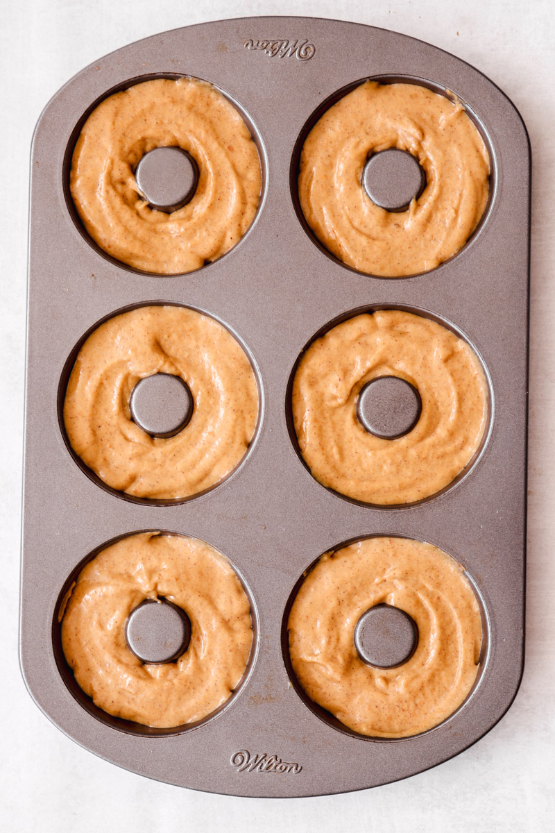overhead image of donut batter in a donut pan