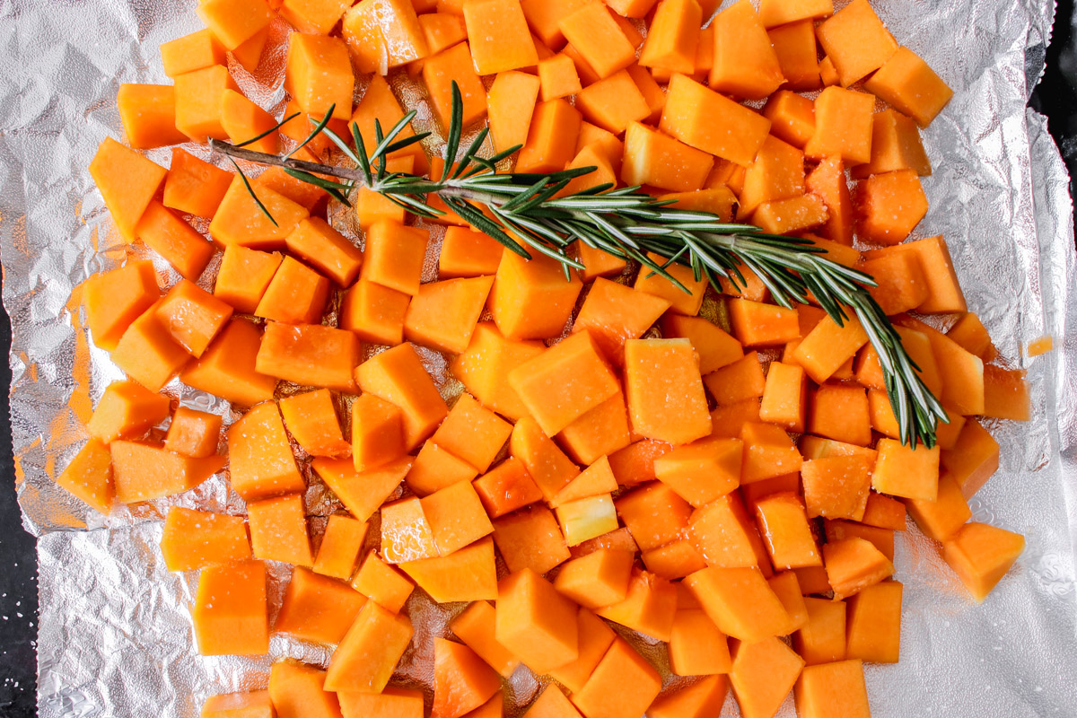 overhead image of roasting butternut squash with fresh rosemary