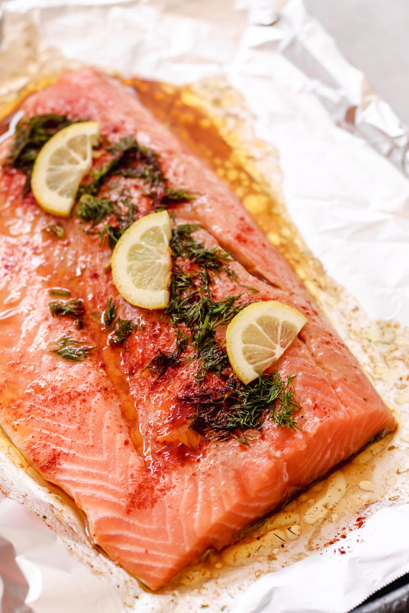 overhead image of salmon on a baking sheet with lemon slices