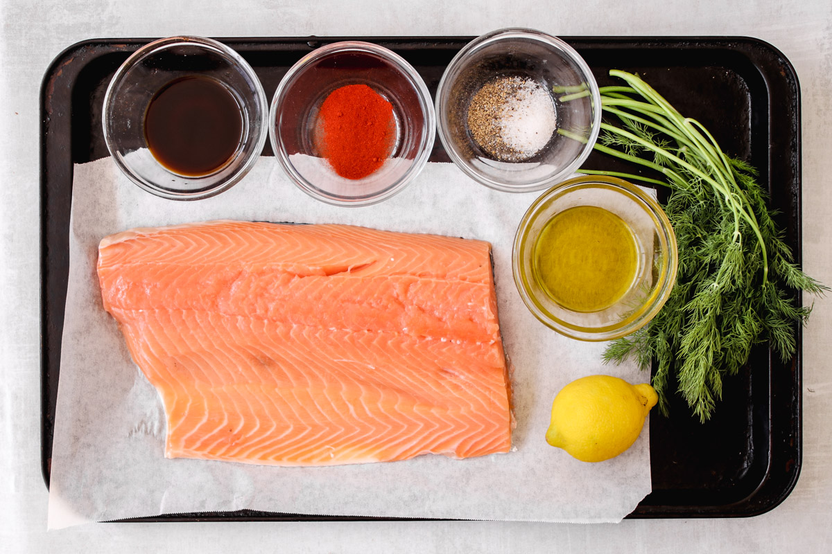 overhead image of salmon and ingredients on a baking sheet