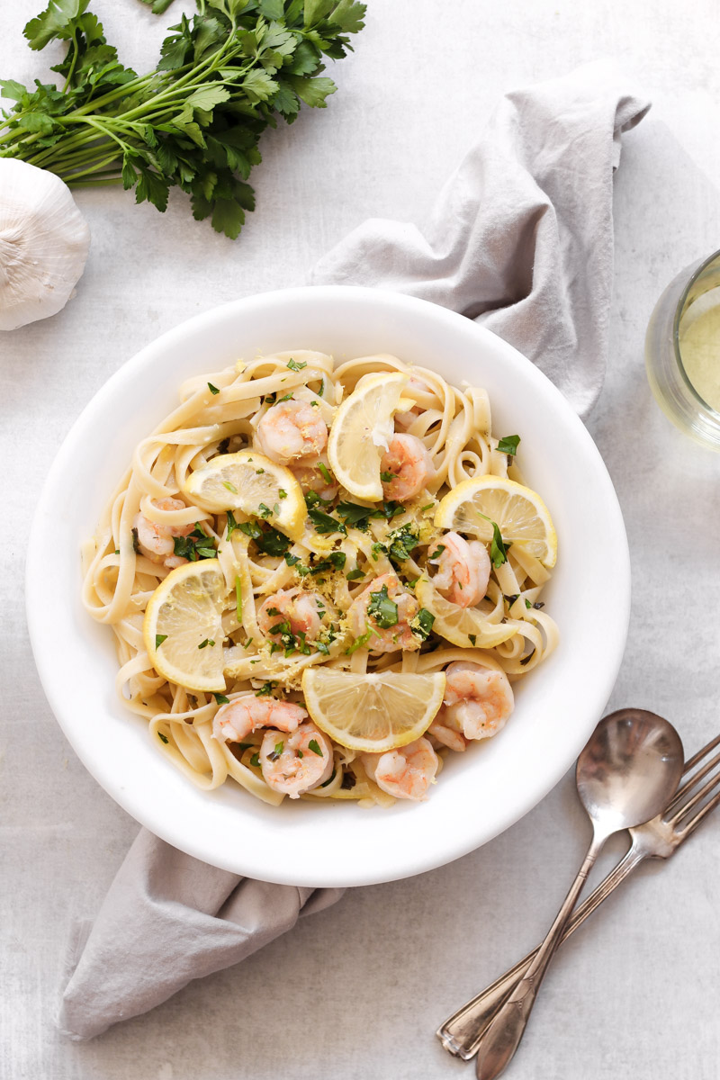 overhead image of shrimp scampi with linguine in a white bowl 