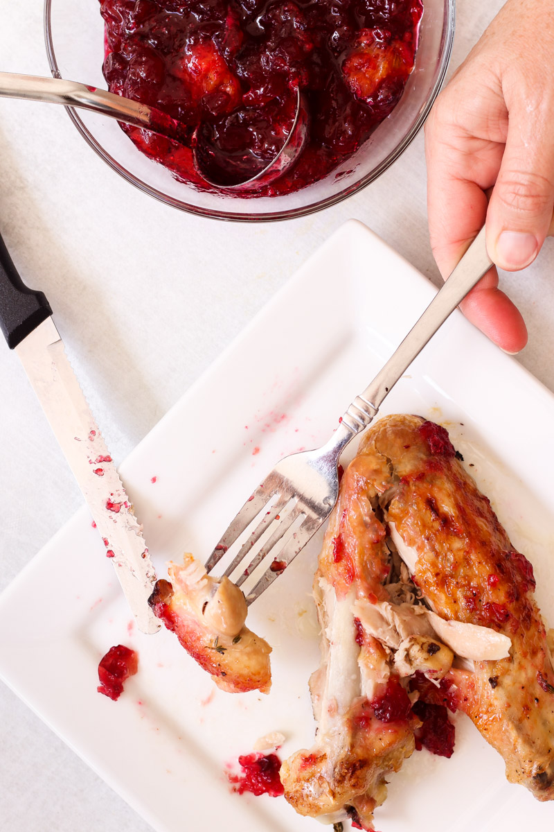 overhead image of a fork and knife cutting meat on a white plate