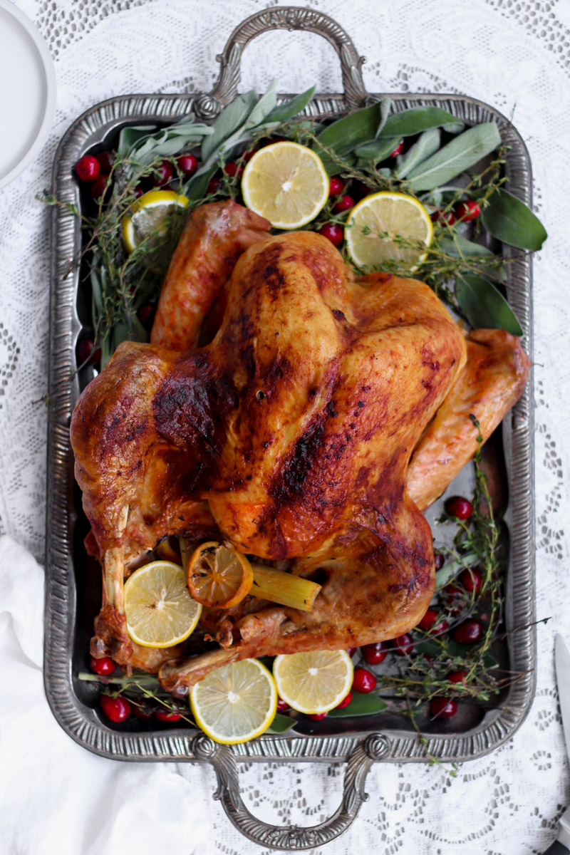 overhead image of an easy roast turkey on a serving platter with fresh herbs.