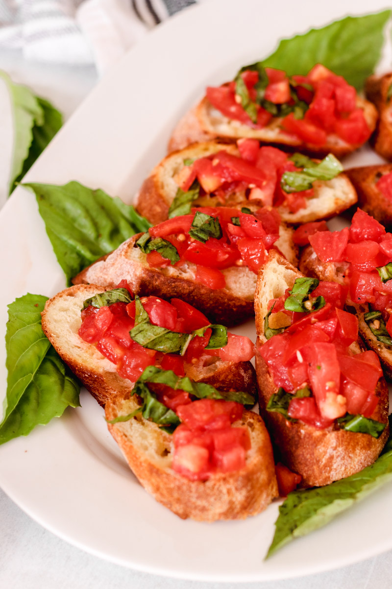 image of bread slices with chopped tomatoes on a white plate and basil.