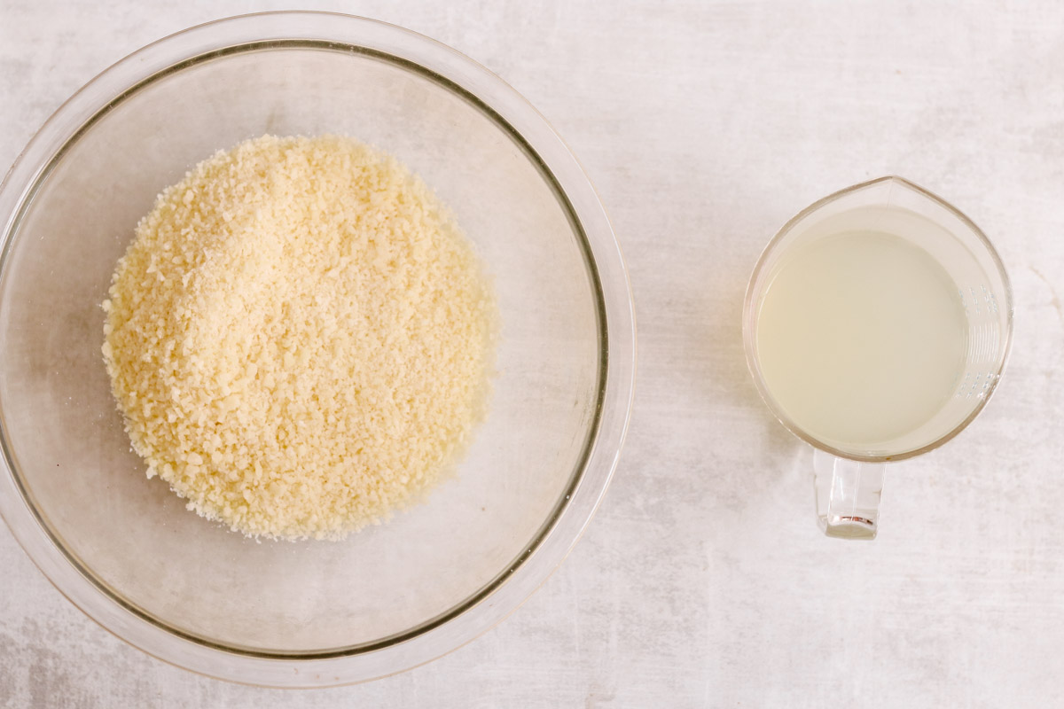 overhead image of grated cheese and liquid in a measuring cup. 