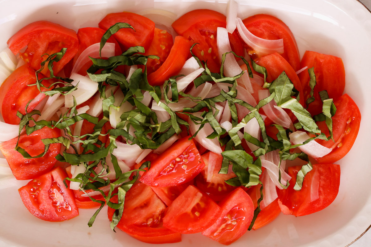 image of sliced tomatoes and fresh herbs on a white plate