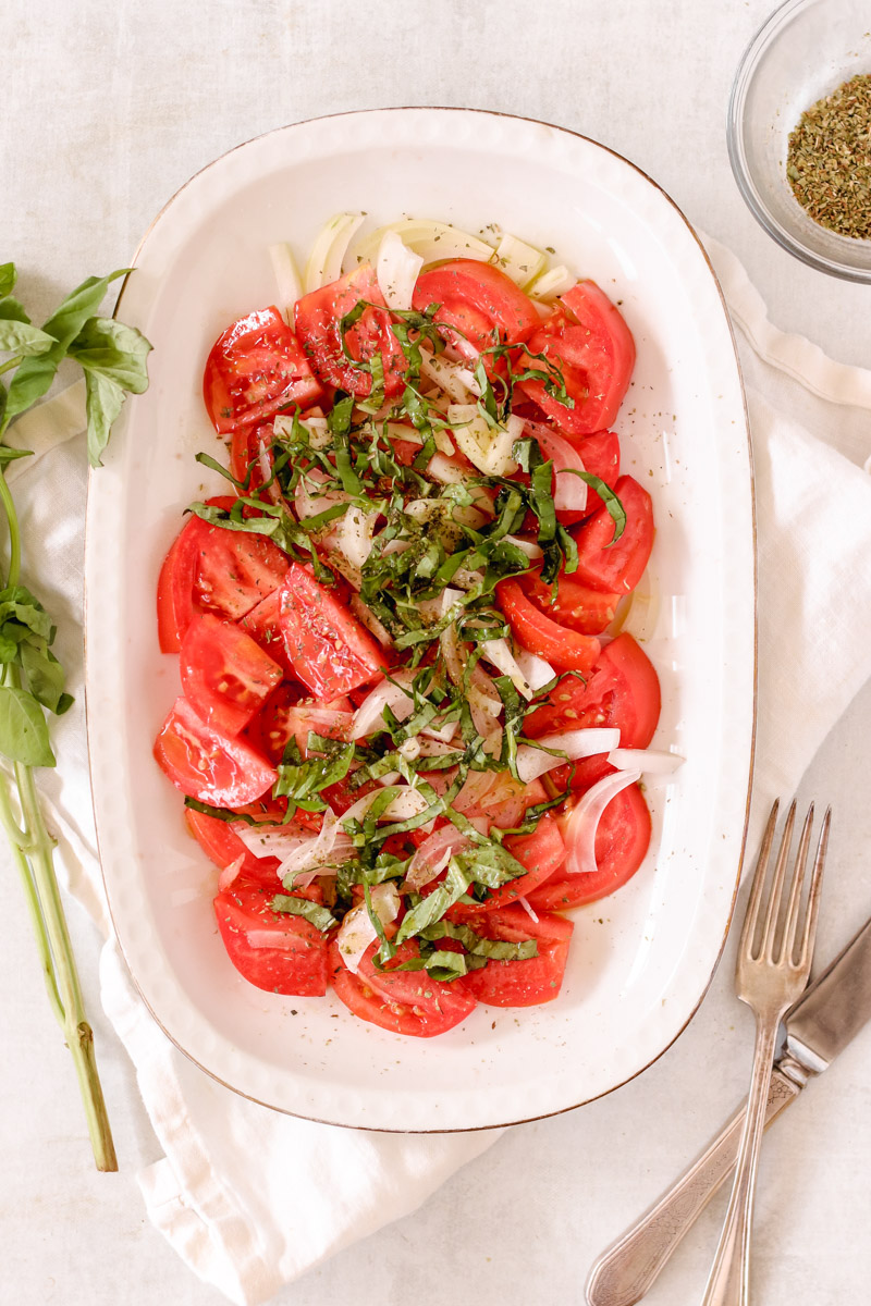 overhead image of a tomato and onion salad on a white plate.