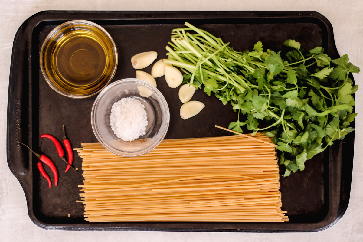 overhead image of ingredients to make spaghetti aglio e olio on a tray.