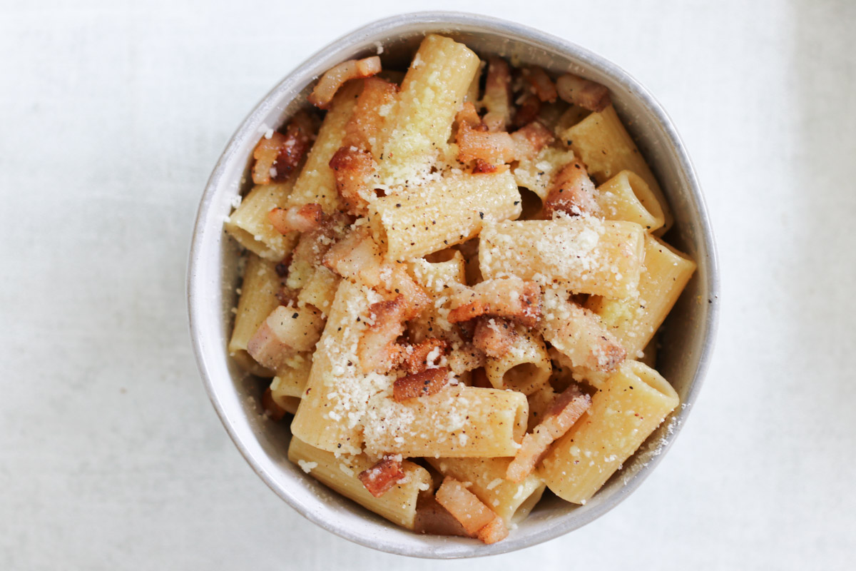 overhead image of pasta in a bowl with grated cheese on top. 