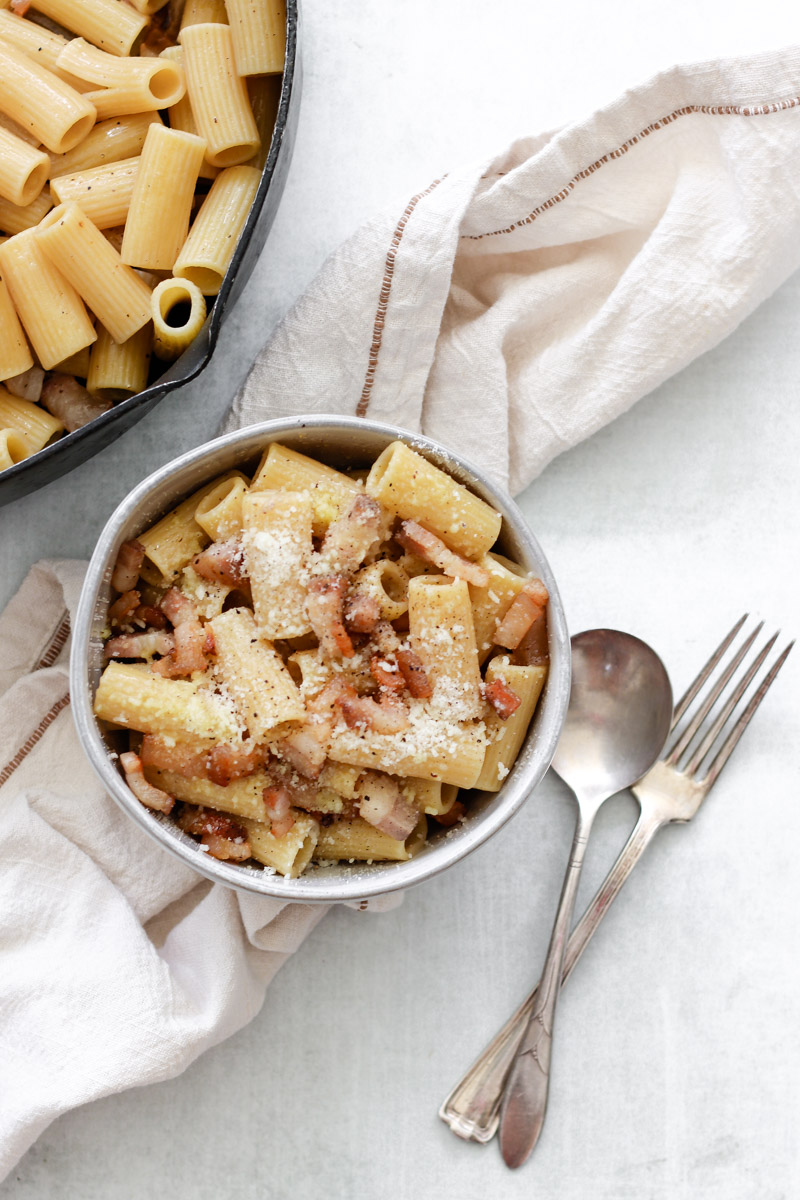 image of pasta in a bowl and napkin in background with fork and spoon.