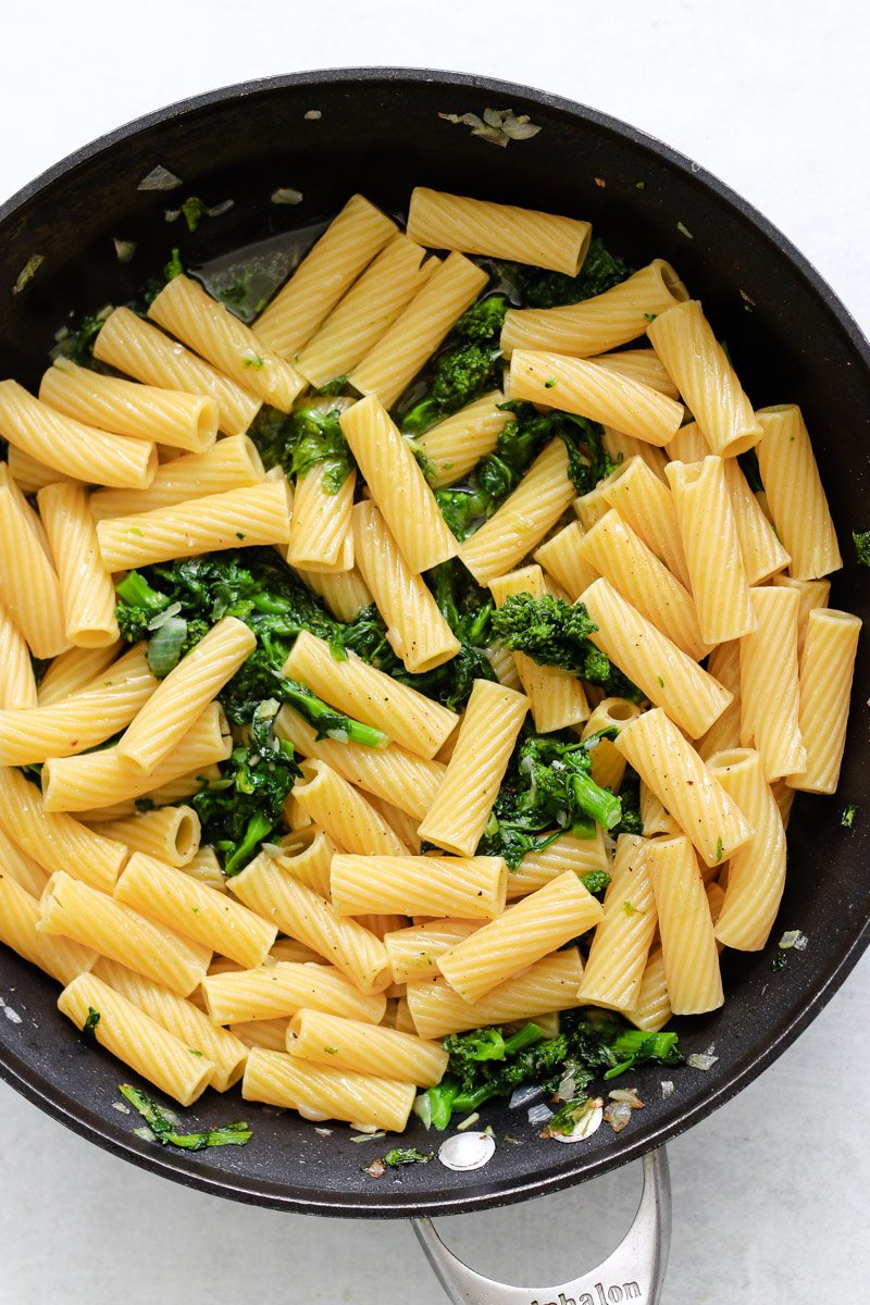 image of pasta in a skillet with a green vegetable.