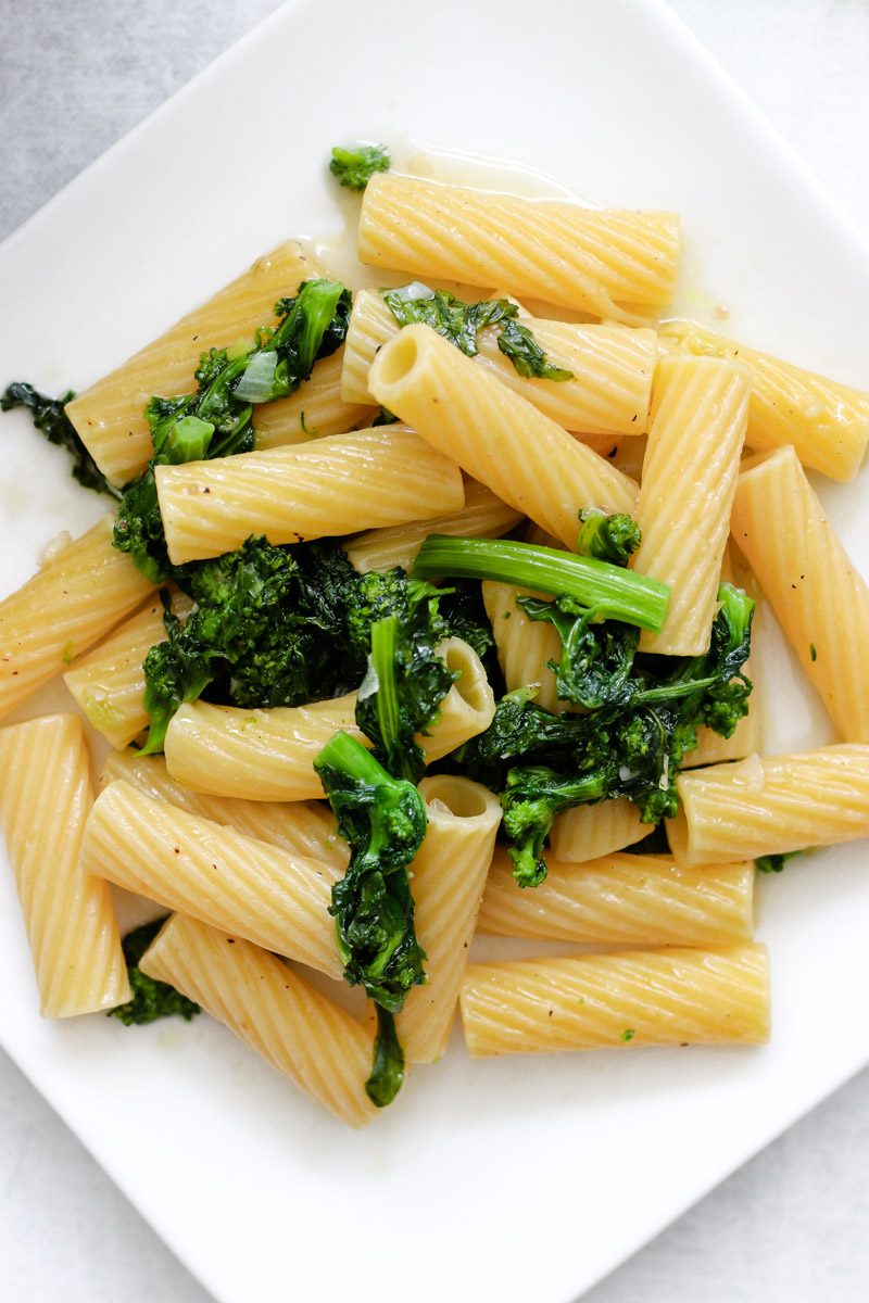 overhead image of pasta with rapini on a white dish. 