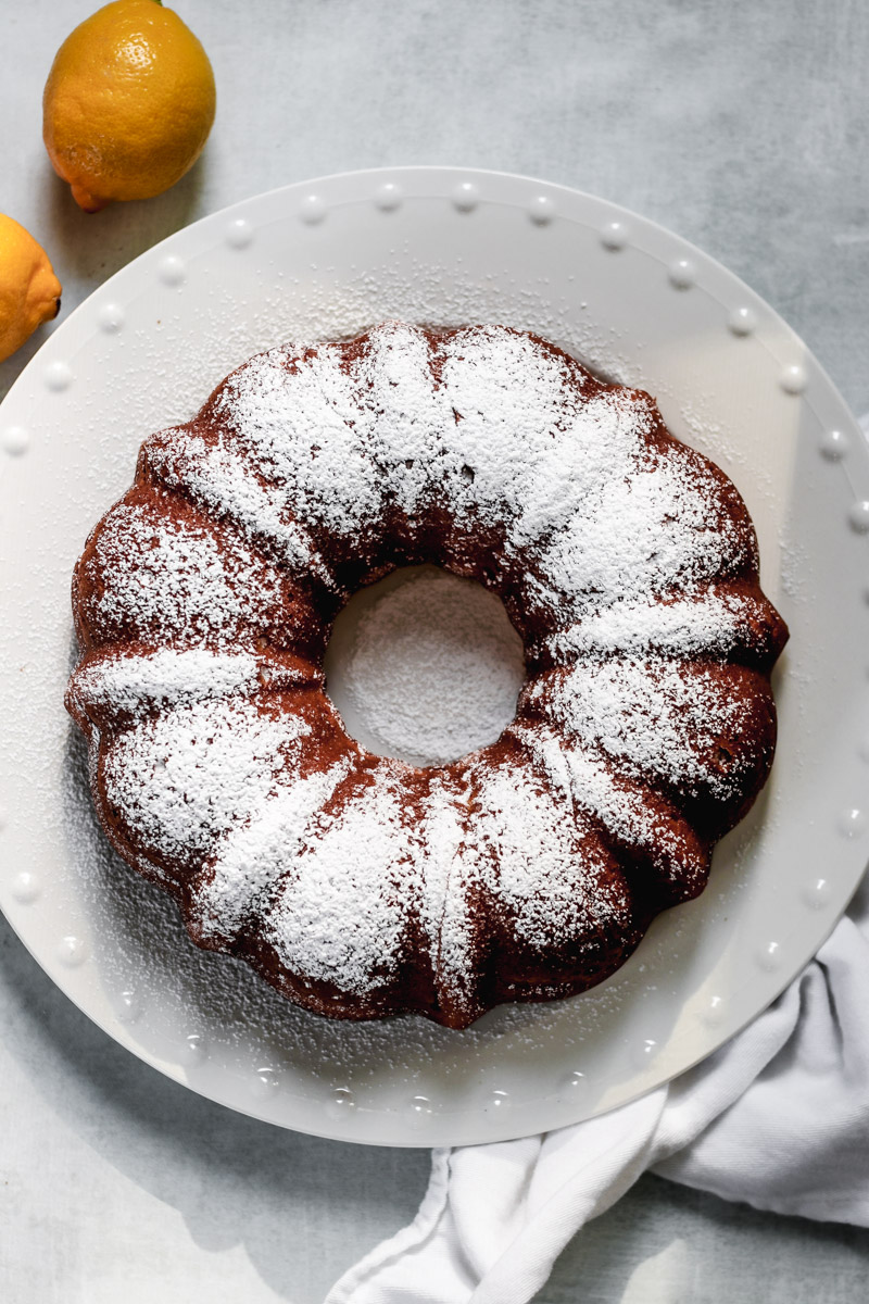 overhead image of a Bundt cake on a white plate with white napkin.