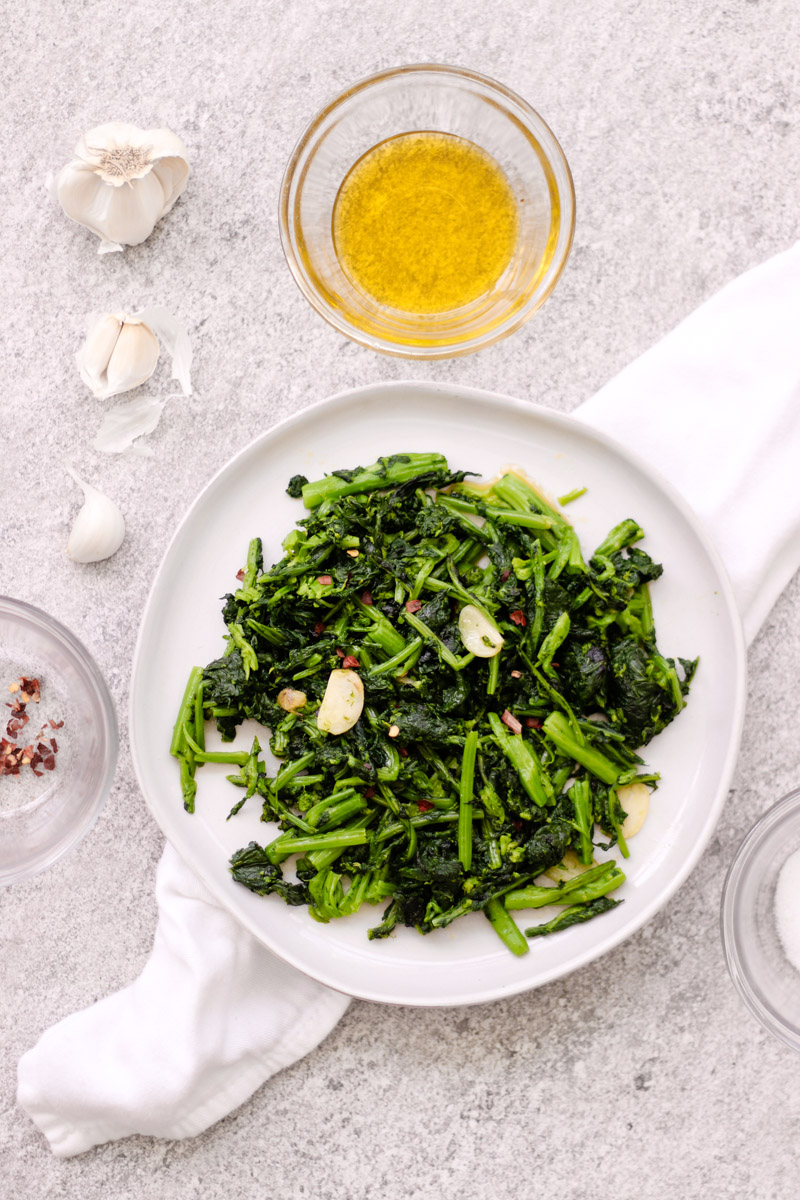 broccoli rabe on white dish with ingredients.