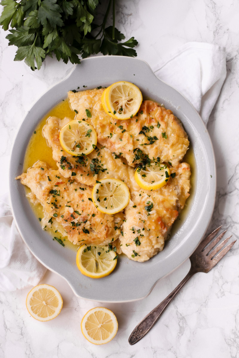 Lemon chicken on a grey dish with parlsey.