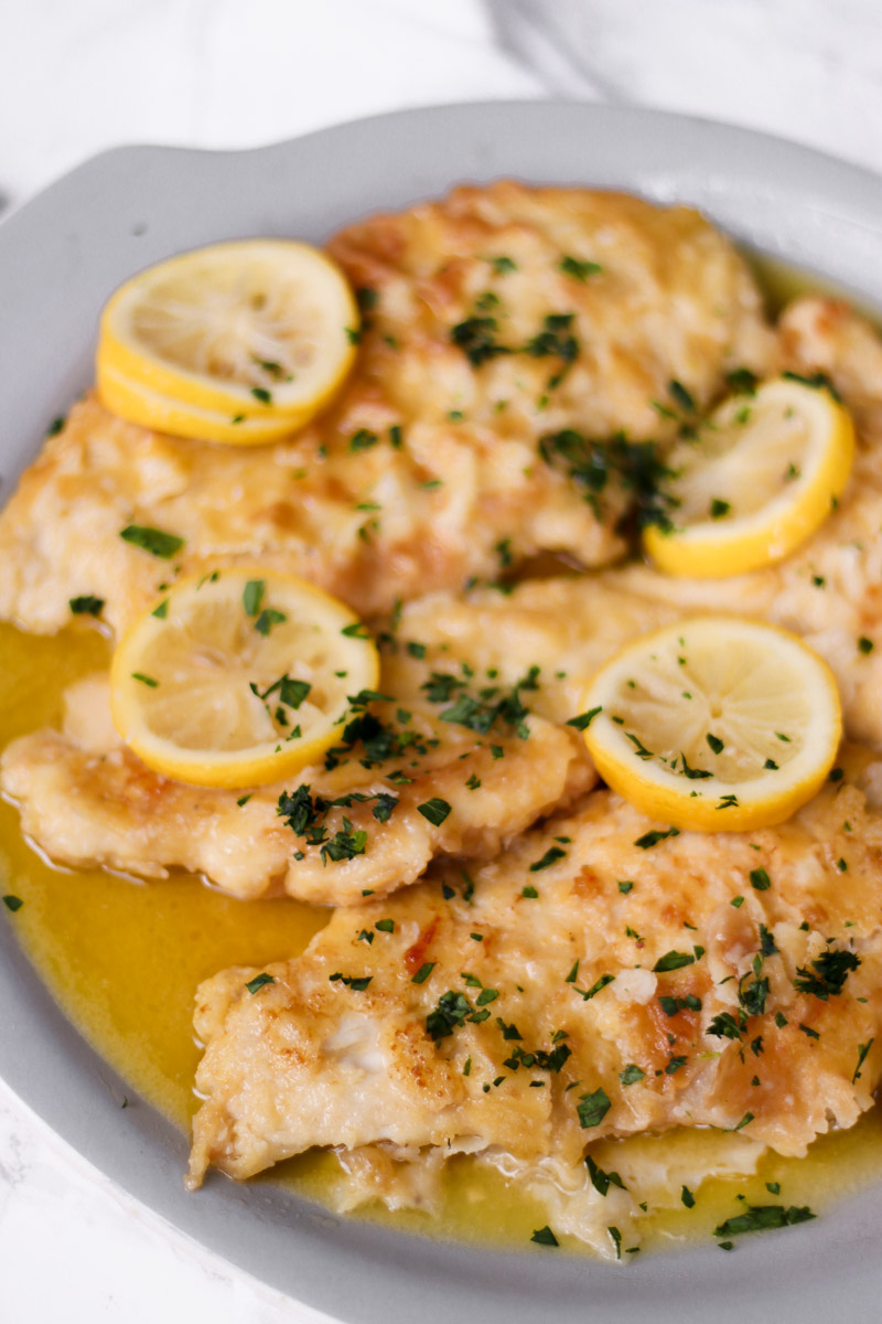 overhead image of lemon chicken on a serving plate with lemon slices. 