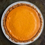 A whole gluten-free pumpkin pie with a crunchy nut-like crust in a round aluminum pan.
