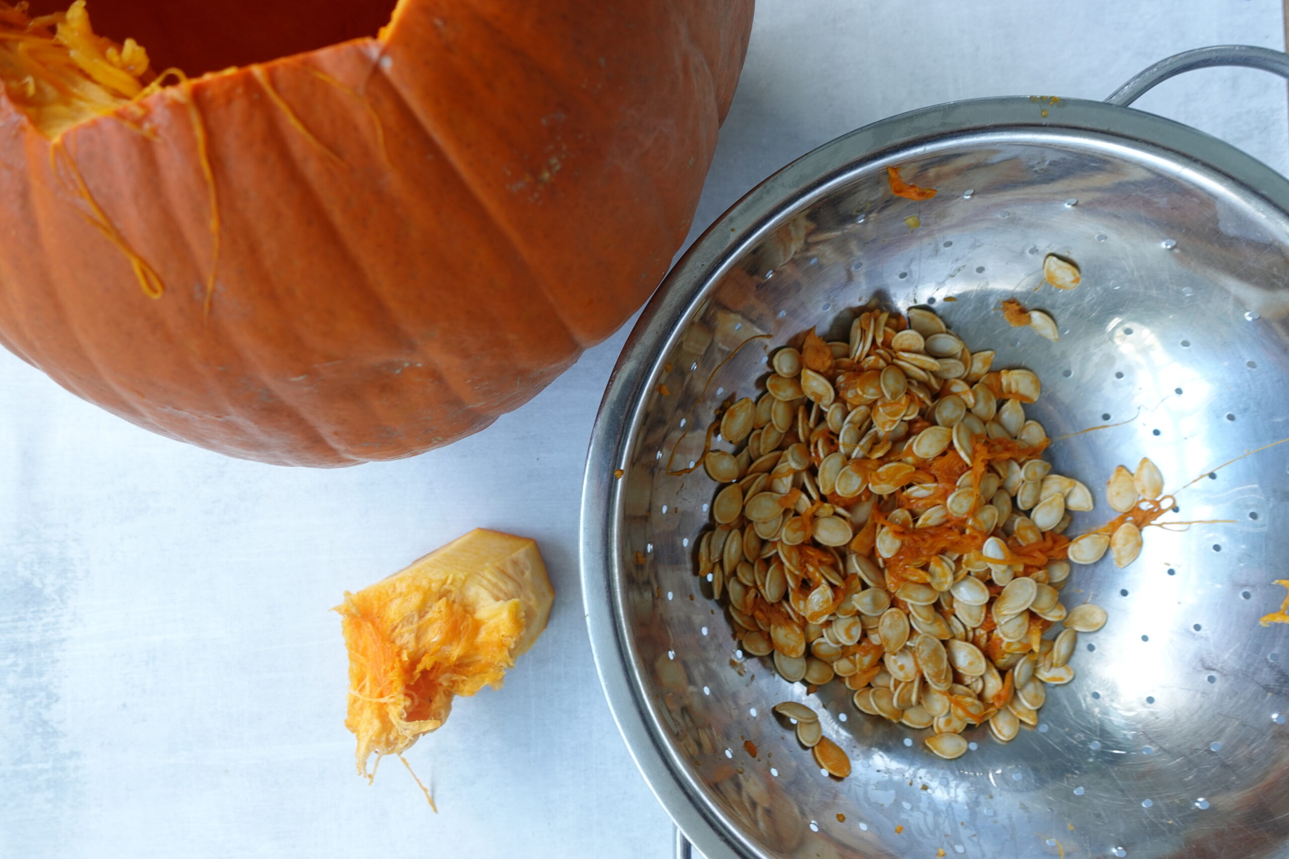 overhead image of cleaning a pumpkin and pumpkin seeds in a colander. 