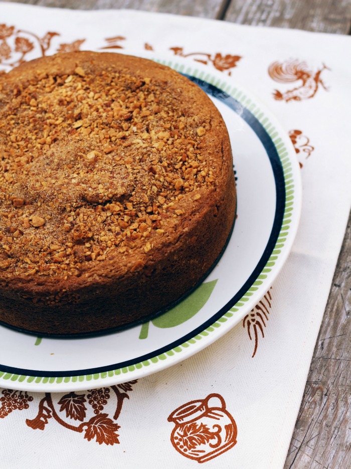 overhead image of an apple cake in a cake pan on top of a dish and a wooden background.