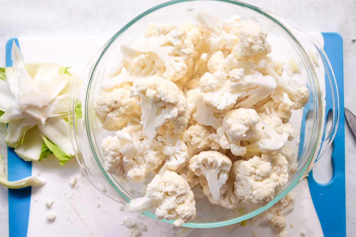 overhead image of prepped cauliflower floret in a glass bowl. 
