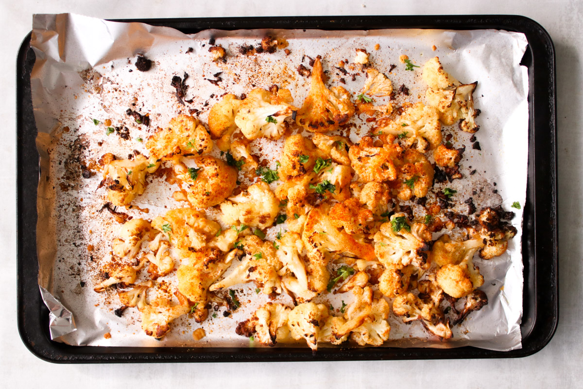 overhead image of roasted cauliflower on a baking sheet. 