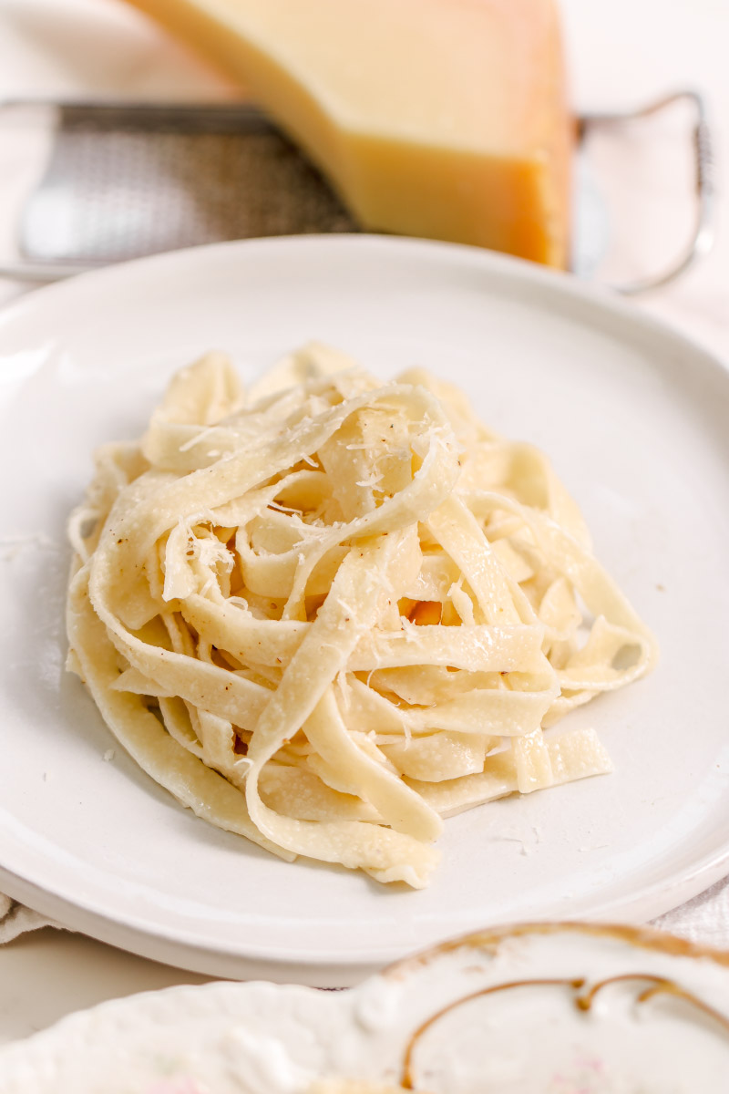 overhead image of pasta with grated cheese on top on a white plate. 